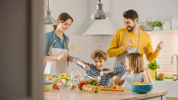 In Kitchen: Family of Four Cooking Together Healthy Dinner, Fool Around and Dance. Mother, Father, Little Boy and Girl, Preparing Salads, Cutting Vegetables. Cute Children Helping their Caring Parents — Stock Photo, Image