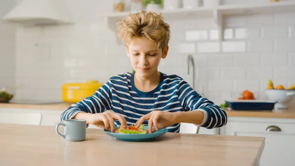 可爱小男孩的画像开始在厨房桌上吃三明治。英俊的男孩吃了一口健康的小点心 — 图库照片