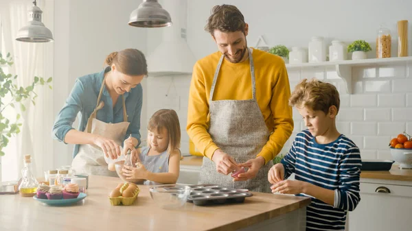 In the Kitchen: Family of Four Cooking Muffins Together. Mother and Daughter Mixing Flour and Water to Create Dough for Cupcakes, Father, Son Preparing Paper Lines for Pans. Children Helping Parents — Stock Photo, Image