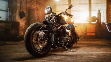 Custom Bobber Motorbike Standing in an Authentic Creative Workshop. Vintage Style Motorcycle Under Warm Lamp Light in a Garage. clipart