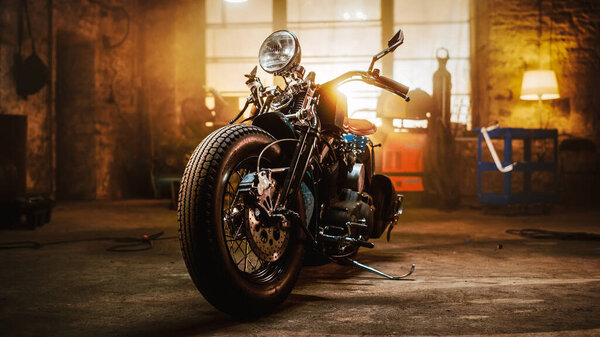 Custom Bobber Motorbike Standing in an Authentic Creative Workshop. Vintage Style Motorcycle Under Warm Lamp Light in a Garage.