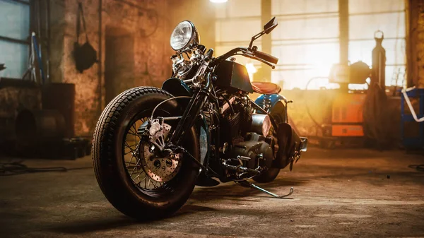 Moto Bobber personnalisée debout dans un atelier créatif authentique. Moto de style vintage sous la lumière chaude de lampe dans un garage. — Photo