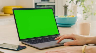 Bir dizüstü bilgisayarla Yeşil Ekranı Kapat. Cihaz, Modern Ev 'de bir mutfak masasında kullanılır. Dokunma pedi kullanan kişi. Sağlıklı Yaşam Tarzı Olan Güneşli Modern Mutfak.