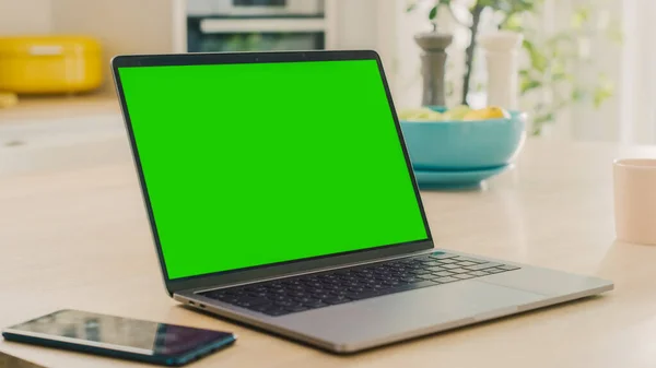 Zamknij makietę Green Screen na laptopie. Urządzenie jest używane na stole kuchennym w nowoczesnym domu. Słoneczna nowoczesna kuchnia z zdrowym stylu życia Vibes. — Zdjęcie stockowe