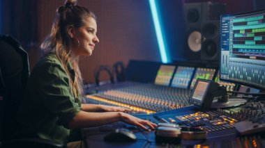 Müzik Kayıt Stüdyosunda çalışan şık, güzel bayan ses mühendisi, Mixing Board Create Song kullanıyor. Kontrol Masasında Çalışan ve Gülümseyen Kız Sanatçı Portresi