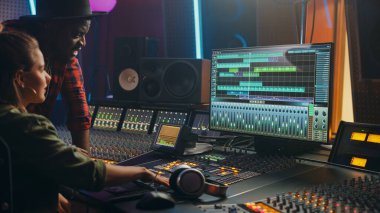 Prodüktör ve Profesyonel Ses Mühendisi birlikte Music Recording Studio 'da yeni bir albüm, Talk, Use Control Desk Equalizer, mix board ve Software to Create Hit Song üzerinde çalışıyorlar. Sanatçı ve Müzisyen