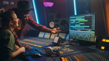 Prodüktör ve Profesyonel Ses Mühendisi birlikte Music Recording Studio 'da yeni bir albüm, Talk, Use Control Desk Equalizer, mix board ve Software to Create Hit Song üzerinde çalışıyorlar. Sanatçı ve Müzisyen