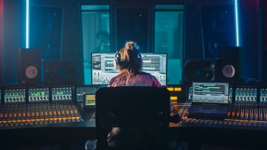 Sanatçı, Müzisyen, Ses Mühendisi, Müzik Kayıt Stüdyosunda Yapımcı, Bilgisayar Ekranı 'nda Song Playing ile Yazılım UI' sını gösteren Kontrol Masasını Kullanıyor. Dans ediyor. Arka Görünüm