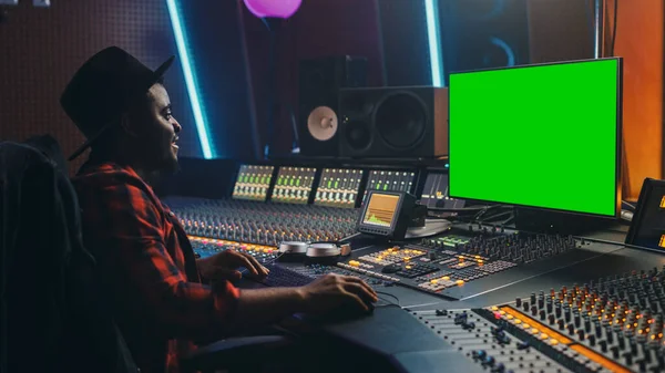 Стильный звукорежиссер, работающий в студии звукозаписи, использует Green Screen, MixBoard Equalizer для создания новых треков и песен. Творческий чёрный музыкант. Портрет с видом сбоку — стоковое фото