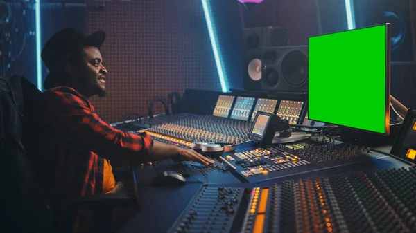 Stylish Audio Engineer Producer, der in Musikaufnahmestudio arbeitet, verwendet Green Screen Chroma Key Computer-Display, Mixer Board Control Desk, um neue Hit Track, Song zu erstellen. Kreativer Black Artist Musiker — Stockfoto