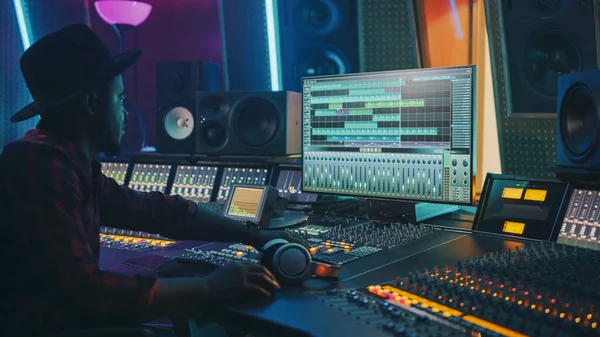 Stylowy inżynier dźwięku Pracujący w studiu nagraniowym, używa tablicy miksującej i oprogramowania do tworzenia nowoczesnej piosenki hitowej. Portret czarnego muzyka pracującego w Control Desk — Zdjęcie stockowe