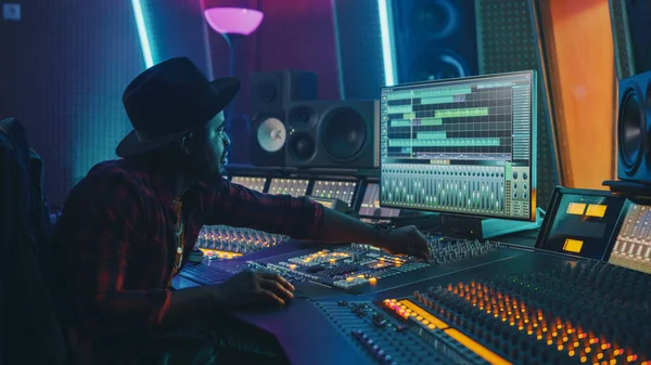 Stylish Audio Engineer Producer Working in Music Record Studio (em inglês). Tela do computador mostrando a interface do usuário do software de estação de trabalho de áudio digital com faixa de reprodução de música. Usa mesa de controle para criar música — Fotografia de Stock