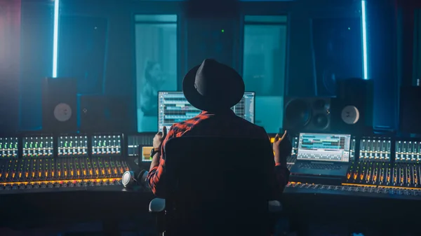 Produzent, Toningenieur verwendet Kontrollpult für die Aufnahme neuer Albumspuren im Musikaufnahmestudio, im schalldichten Raum singt Musiker, Künstler, Interpret ein Lied aus neuem Album. Zurück zur Ansicht — Stockfoto