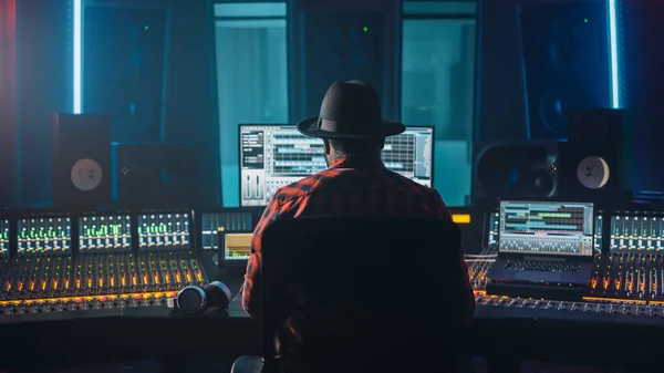 Artista con estilo, Músico, Ingeniero de audio, Productor se lleva a cabo en su escritorio de control en Music Record Studio, utiliza el programa de pantalla de computadora Interfaz de usuario del software DAW con reproducción de canciones. Vista trasera —  Fotos de Stock