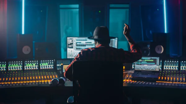 Artist, Musician, Audio Engineer, Producer in Music Record Studio, Uses Control Desk with Computer Screen showing Software UI with Song Playing. Celebrates Success with Raised Hands, Dances. Back View — Stock Photo, Image