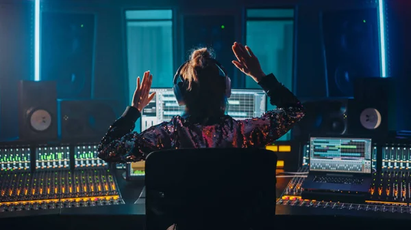 アーティスト、ミュージシャン、オーディオエンジニア、音楽録音スタジオのプロデューサーは、曲再生でソフトウェアUIを示すコンピュータ画面でコントロールデスクを使用します。復活した手で成功を祝う,ダンス.バックビュー — ストック写真