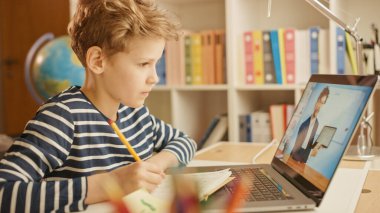 Akıllı çocuk öğretmeniyle video görüşmesi için dizüstü bilgisayar kullanıyor. Ekranda Öğretmen Sınıftan Konuyu Açıklarken Çevrimiçi Ders Gösteriliyor, Çocuk Bilgi Yazıyor. E-Eğitim Mesafesi Öğrenme