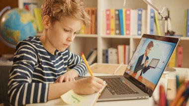 Akıllı çocuk öğretmeniyle video görüşmesi için dizüstü bilgisayar kullanıyor. Ekranda Öğretmen Sınıftan Konuyu Açıklarken Çevrimiçi Ders Gösteriliyor, Çocuk Bilgi Yazıyor. E-Eğitim Mesafesi Öğrenme
