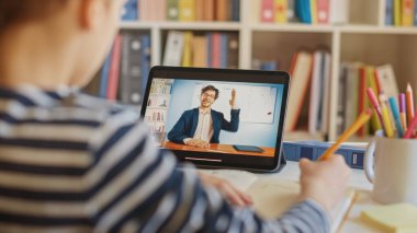Akıllı çocuk öğretmeniyle video görüşmesi için dijital tablet kullanıyor. Ekranda Sınıftan Konuyu Açıklayan Öğretmenle Çevrimiçi Ders Gösteriliyor. E-Eğitim Mesafesi Öğrenme, Ev Eğitimi
