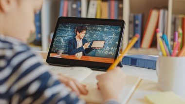 Akıllı çocuk öğretmeniyle video görüşmesi için dijital tablet kullanıyor. Ekranda Sınıftan Konuyu Açıklayan Öğretmenle Çevrimiçi Ders Gösteriliyor. E-Eğitim Mesafesi Öğrenme, Ev Eğitimi