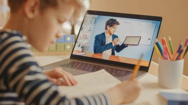 Akıllı çocuk öğretmeniyle video görüşmesi için dizüstü bilgisayar kullanıyor. Ekranda Sınıftan Konuyu Açıklayan Öğretmenle Çevrimiçi Ders Gösteriliyor. E-Eğitim Mesafesi Öğrenme, Ev Eğitimi.