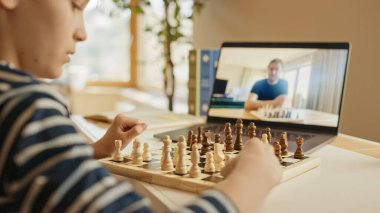 Uzaktan Akrabası ya da amcasıyla Satranç Oynayan Zeki Küçük Çocuk, Video Çağrı için Dizüstü bilgisayar kullanıyor. Uzaktan Online Eğitim, E-Eğitim, Aileyle İletişim, Evde Eğitim.