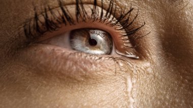 Ağlayan Göz 'ün Macro Shot' unu yakın çekim. İris 'te Doğal Açık Mavi, Sarı ve Kahverengi Pigmentasyonlu Genç Güzel Kadın. Mascara kirpiklere uygulanır. Gözyaşları akıyor.