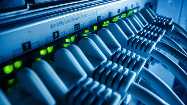 Макро-шот: Кабели передачи данных Ethernet подключаются к маршрутизатору с мигающими огнями. Телекоммуникации: RJ45 Internet Connectors Plugged into Modem LAN Hub. Работа системы защищенного центра обработки данных
