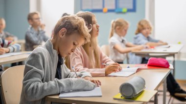 Çeşitli Çocuklar İlköğretim Sınıfı Öğretmenlerinin Ders Vermesini Dikkatle Dinliyor. Egzersiz kitaplarında yazan, sınavlara giren, sınavlara giren zeki çocuklar. Kırık Kollu Çocuk.