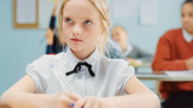 İlköğretim Okulu Sınıfı 'nda Zeki ve Sevimli Beyaz Bir Kızın Portresi Egzersiz Defteri Yazıyor. Çeşitli Çocuk Sınıfı Özenle Çalışıyor ve Yeni Şeyler Öğreniyor