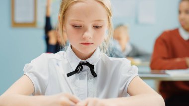 İlköğretim Okulu Sınıfı 'nda Zeki ve Sevimli Beyaz Bir Kızın Portresi Egzersiz Defteri Yazıyor. Çeşitli Çocuk Sınıfı Özenle Çalışıyor ve Yeni Şeyler Öğreniyor