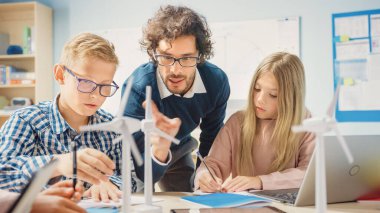 İlköğretim Okulu Sınıfı: Heyecanlı Öğretmenin Tablet Bilgisayarı Tutması Zeki Genç Çocuklara Ders Açıklıyor. Çocuklar Programlama Dili Öğreniyor, İnternet Güvenliği ve Bilgi Teknolojisi