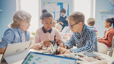 İlköğretim Okulu Robotik Sınıfı: Coşkulu Öğretmen İnşa Etme ve Programlama Robotu olan Çeşitli Zeki Çocuklar Grubu. Yazılım Öğrenen Çocuklar Tasarım ve Yaratıcı Robot Mühendisliği