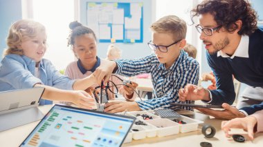 İlköğretim Okulu Robotik Sınıfı: Coşkulu Öğretmen İnşa Etme ve Programlama Robotu olan Çeşitli Zeki Çocuklar Grubu. Yazılım Öğrenen Çocuklar Tasarım ve Yaratıcı Robot Mühendisliği