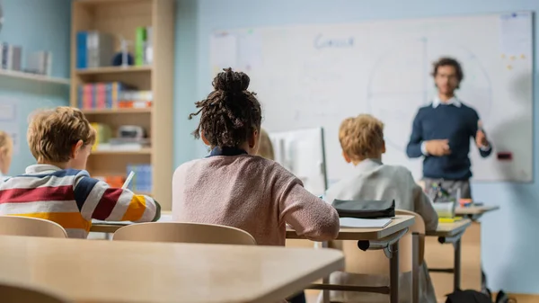 Enthousiaste Leraar legt lessen en vragen uit uit een klaslokaal vol heldere en diverse kinderen. In Elementary School Group of Smart Multiethnic Kids Learning Science en creatief denken — Stockfoto