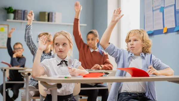 Aula Primaria de Niños Diversos Escuchando al Maestro Dando una Lección. Todo el mundo levanta la mano sabiendo la respuesta correcta. Niños pequeños en la escuela Aprendizaje Ciencia, Pensamiento creativo —  Fotos de Stock