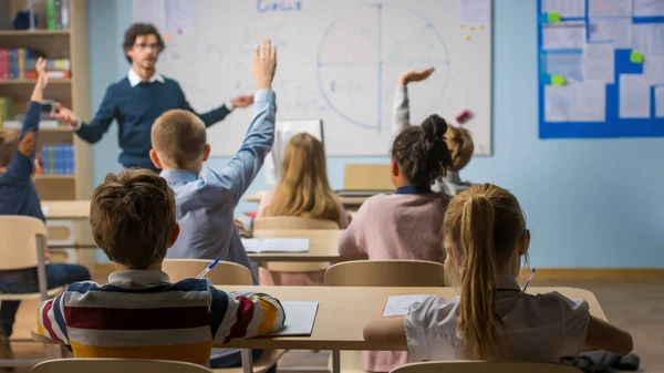 Caring Teacher Explains Lesson to a Classroom Full of Diverse Children. In School with Group of Smart Multiethnic Kids Learning Science, Whole Classroom Raising Hands Knowing Answer. — Stock Photo, Image