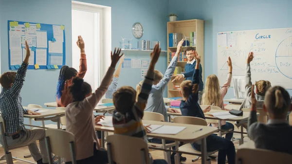 Caring Teacher Explains Lesson to a Classroom Full of Bright Diverse Children. In Elementary School with Group of Smart Multiethnic Kids Learning Science, Whole Classroom Raising Hands Knowing Answer — Stock Photo, Image