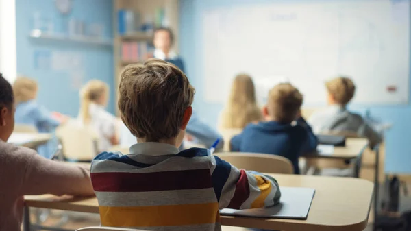 Caring Teacher Explains Lesson to a Classroom Full of Bright Diverse Children (dalam bahasa Inggris). Di Sekolah Dasar dengan Kelompok Cerdas Multietnis Anak Belajar Sains. — Stok Foto