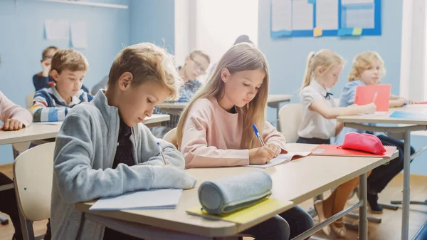 Sala de aula elementar de crianças diversas Escrevendo em cadernos de exercícios, fazendo testes, exames. Jovens e brilhantes na escola ouvindo atentamente a sua lição de dar professor. Aprendizagem infantil — Fotografia de Stock