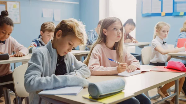 Sala de aula elementar de crianças diversas Escrevendo em cadernos de exercícios, fazendo testes, exames. Jovens e brilhantes na escola ouvindo atentamente a sua lição de dar professor. Aprendizagem infantil — Fotografia de Stock