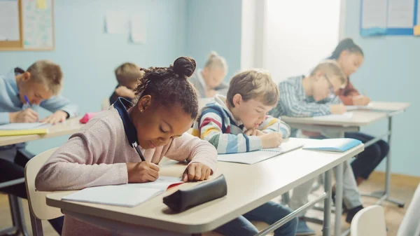 Elemi Osztályterem Diverzum Bright Children Figyelmesen hallgatva a tanár így leckét. Brilliáns fiatal gyerekek az iskolában írás gyakorlása jegyzetfüzetek, tesztelés. — Stock Fotó