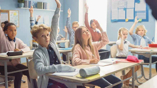 A gyermekek általános osztályterme Figyelmesen hallgatja a tanárukat, amint leckét ad. Mindenki felemeli a kezét, tudván a helyes választ. Fiatal gyerekek az iskolai tanulásban Tudomány és kreatív gondolkodás — Stock Fotó