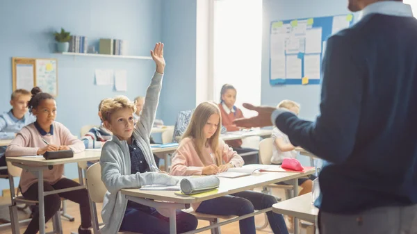 Aula elemental de niños escuchando atentamente a su maestro dando lección. Todo el mundo levanta la mano sabiendo la respuesta correcta. Niños pequeños en la escuela Aprendizaje Ciencia y pensamiento creativo — Foto de Stock