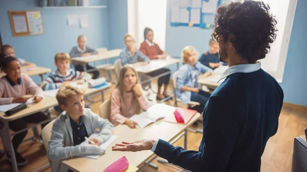 Aula Primaria de Diversos Niños Brillantes Escuchando al Maestro Dando una Lección. Niños brillantes en el aprendizaje escolar. Maestro sobre tiro de hombro —  Fotos de Stock