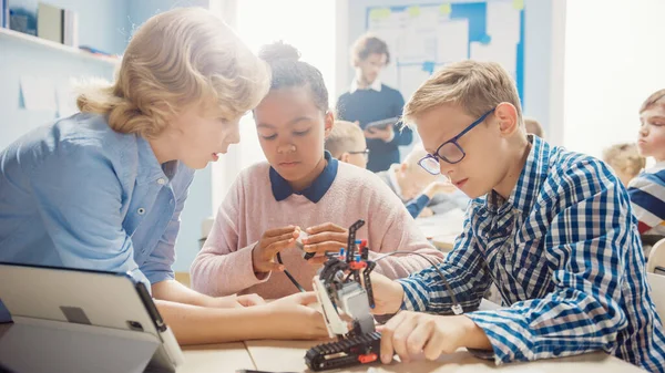 Δημοτικό Σχολείο Robotics Classroom: Διαφορετική ομάδα λαμπρή παιδιά με Ενθουσιαστικός Δασκάλα Κτίριο και Ρομπότ Προγραμματισμού. Παιδιά που μαθαίνουν σχεδιασμό λογισμικού και δημιουργική ρομποτική μηχανική — Φωτογραφία Αρχείου