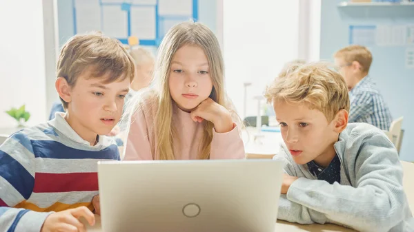 Elementary School Classroom: Diverse Group of Brilliant Children Using Laptop Computer for Software Programming, Talking and Working as a Team (en inglés). Diseño de software de aprendizaje para niños y pensamiento creativo — Foto de Stock