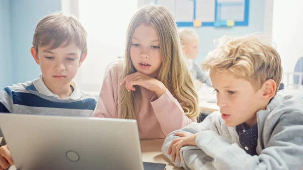 Elementary School Classroom: Diverse Group of Brilliant Children Using Laptop Computer for Software Programming, Talking and Working as a Team (en inglés). Diseño de software de aprendizaje para niños y pensamiento creativo — Foto de Stock