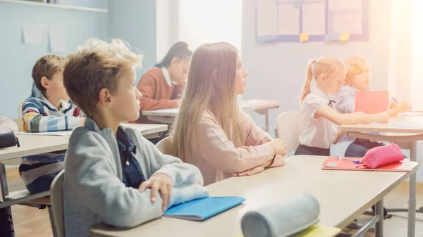 Aula Primaria de Diversos Niños Brillantes escuchando atentamente a su Maestro dando Lección. Niños jóvenes brillantes en la escuela que aprenden a ser grandes científicos, médicos, programadores, astronautas —  Fotos de Stock