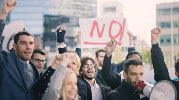 Multikulturell vielfältige Büromanager und Geschäftsleute, die draußen auf einer Straße Streikposten machen. Männer und Frauen schreien nach Gerechtigkeit, halten ein Megafon, Schilder und Plakate in die Höhe. Streik in der Wirtschaftskrise. — Stockfoto